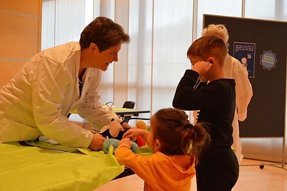 Kind hört in der Notfallstation der Stofftierklinik die Lunge seines Mickey-Maus-Stofftiers ab