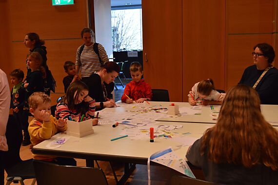 Kinder und ihre Begleitpersonen malen zusammen am Tisch