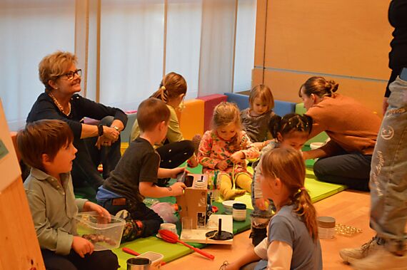 Kinder und ihre BegleiterInnen spielen mit Alltagsgegenständen